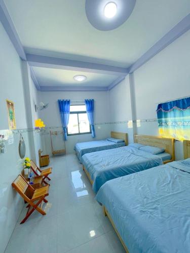a bedroom with three beds and a table in it at Homestay Hoàng Phúc in Cu Lao Thu