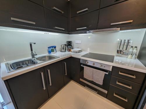 a kitchen with black cabinets and a sink at Konnet Apartment in Rhodes Town