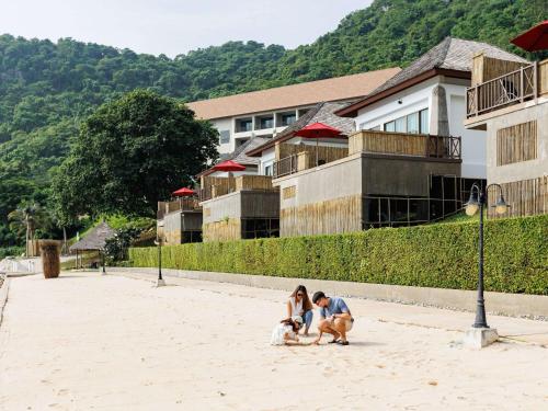 a man and a woman sitting on the street at Novotel Koh Si Chang in Ban Phanu Rangsi