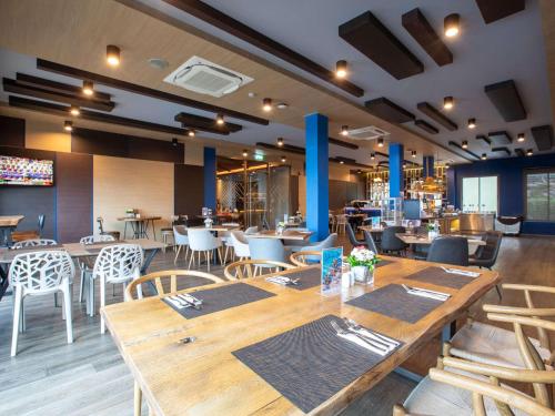 a restaurant with wooden tables and chairs in a room at Novotel Koh Si Chang in Ban Phanu Rangsi