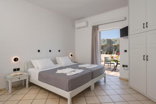 a white bedroom with a bed and a balcony at Hotel Caretta Beach in Gerani