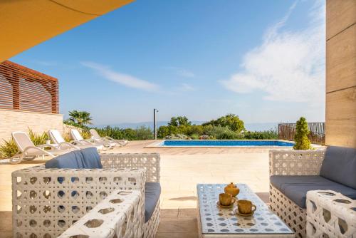 een patio met stoelen, een tafel en een zwembad bij Villa Luce in Labin