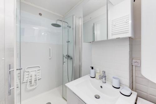 uma casa de banho branca com um lavatório e um chuveiro em Le Central tout équipé ! em Toulouse