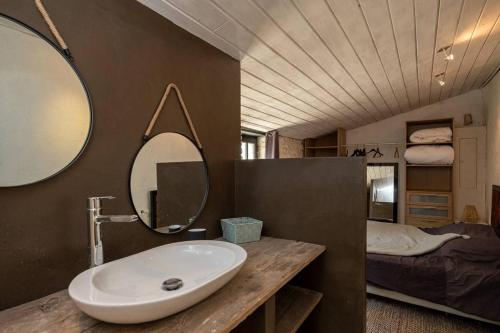 uma casa de banho com um lavatório, um espelho e uma cama em Charmante maison dans venelle fleurie em Sainte-Marie-de-Ré