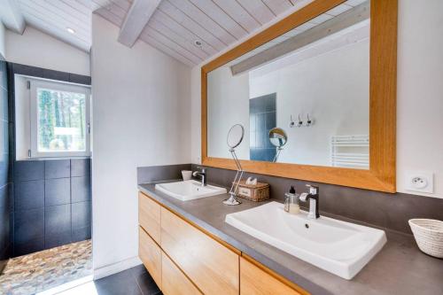 a bathroom with two sinks and a large mirror at Maison au calme en lisière de forêt avec piscine chauffée in Ars-en-Ré