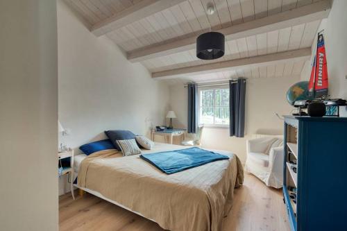 a bedroom with a bed with blue pillows on it at Maison au calme en lisière de forêt avec piscine chauffée in Ars-en-Ré