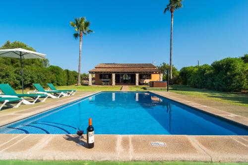 una bottiglia di vino appoggiata su una sporgenza accanto a una piscina di Finca Pollentia a Alcudia