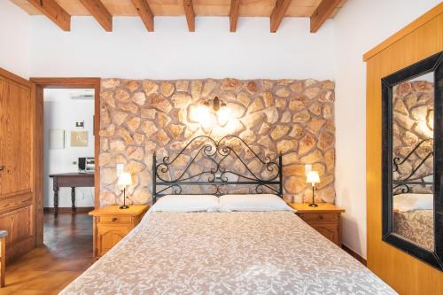 a bedroom with a bed and a stone wall at Finca Pollentia in Alcudia