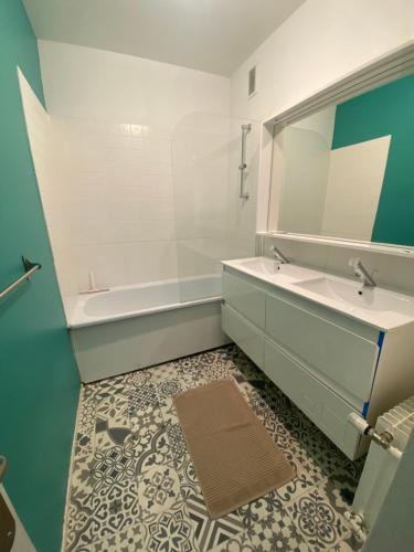 une salle de bain avec un lavabo, une baignoire et un miroir dans l'établissement Berlioz Appartement spacieux et lumineux 