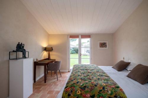une chambre avec un lit, un bureau et une fenêtre dans l'établissement Maison galerie dans un jardin de 1200m2, au Bois-Plage-en-Ré