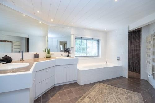 La salle de bains blanche est pourvue d'une baignoire, d'un lavabo et d'une baignoire. dans l'établissement Maison galerie dans un jardin de 1200m2, au Bois-Plage-en-Ré