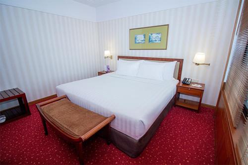a bedroom with a large white bed and two tables at Redtop Hotel & Convention Center in Jakarta