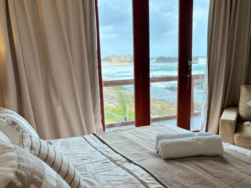 a bedroom with a bed with a view of the ocean at On the Rocks @ Eersterivier in Eersterivierstrand