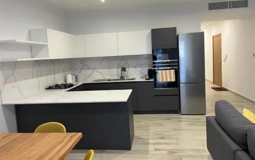 een keuken met een koelkast, een tafel en een bank bij St Julians New 3 Bedroom Luxury Apartment in St Julian's