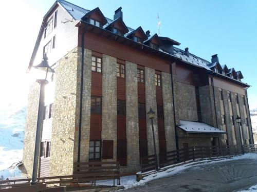 a large wooden building with snow on the ground at res form c 2 d prima in Sallent de Gállego