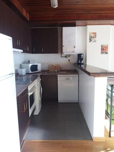 a small kitchen with white appliances and brown cabinets at res form c 2 d prima in Sallent de Gállego
