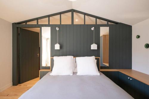 une chambre avec un grand lit avec des oreillers blancs dans l'établissement Maison familiale rénovée avec piscine quartier de la Cible, à Saint-Martin-de-Ré
