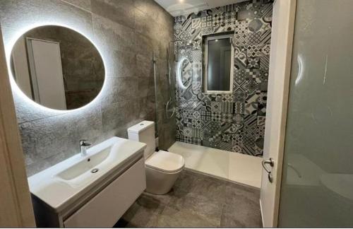 een badkamer met een wastafel, een toilet en een spiegel bij St Julians New 3 Bedroom Luxury Apartment in St Julian's