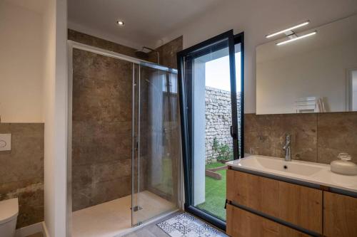 een badkamer met een douche, een wastafel en een bad bij Maison familiale neuve avec piscine chauffée in La Noue