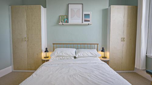 a bedroom with a bed with two lamps and two cabinets at Burlington Mansions - Stunning Coastal Apartment in Bournemouth