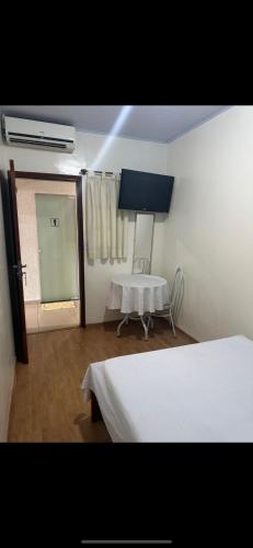 a room with two beds and a table and a window at Hotel Lara's in Ribeirão Preto