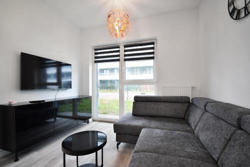 a living room with a couch and a flat screen tv at RentPlanet - Apartament Bałtycka II in Kołobrzeg