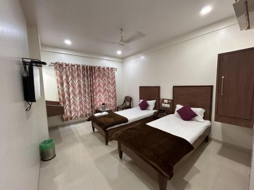 a bedroom with two beds and a television in it at Hotel Horizon Vapi in Vapi