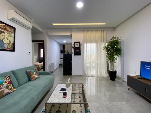 ein Wohnzimmer mit einem grünen Sofa und einem TV in der Unterkunft chez vicky in Tunis