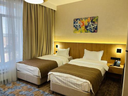 Zhezqazghan的住宿－KHAN ORDASY，酒店客房设有两张床和窗户。