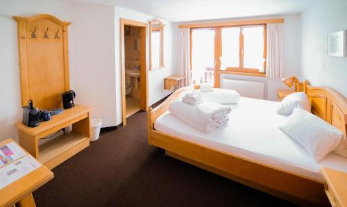 1 dormitorio con 1 cama grande con almohadas blancas en Hotel Postigliun Sedrun, en Sedrun