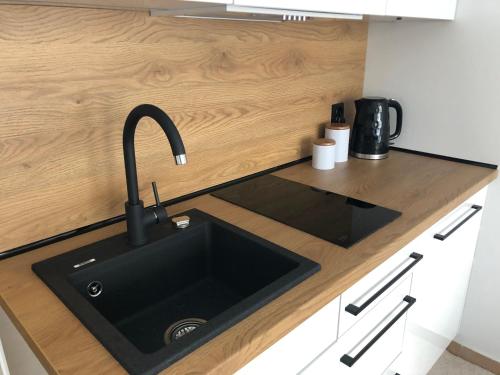 a kitchen with a black sink in a counter at Apartament Planeta 202 - tylko 100 m do plaży, odnowiony w 2024 in Mielno