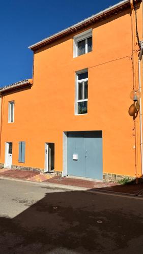 un bâtiment orange avec un garage bleu dans l'établissement Duplex proche mer, avec swimspa terrasse, jardin et barbecue, à Lapalme