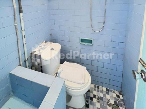 a blue bathroom with a toilet and a sink at LestInn Homestay Monjali Mitra Reddoorz in Kejayan