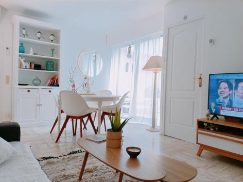 uma sala de estar branca com uma mesa e uma televisão em Appartement cosy centre ville em Sainte-Maxime