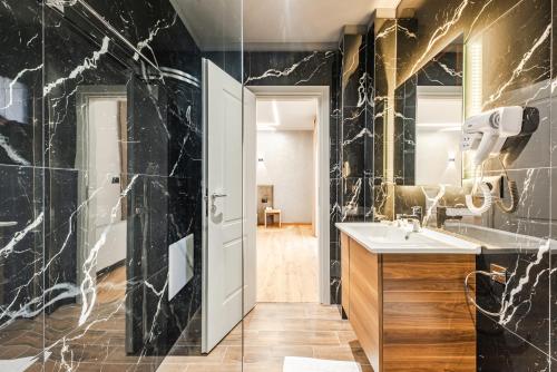 a bathroom with black marble walls and a sink at Relax Inn Hotel Durres in Durrës