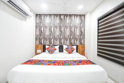 - une chambre avec un grand lit blanc et des oreillers colorés dans l'établissement FabHotel Prime Palace View, à Vadodara
