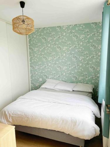 een slaapkamer met een bed met een groene muur bij Paris JO / Proche Aéroport CDG / Centre Chantilly in Chantilly