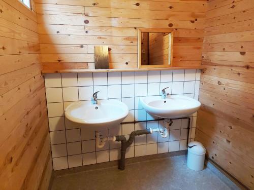 two sinks in a bathroom with wooden walls at Gemütliches Tiny House Uggla im Wald am See in Torestorp