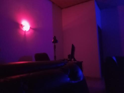 een donkere kamer met een bed en een rood licht bij Crale and Busino in Port Harcourt