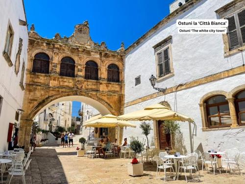 an archway with tables and umbrellas next to a building at La maison de Rosetta al mare in Specchiolla 