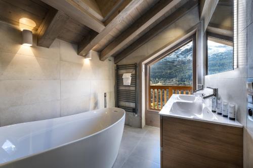 a bathroom with a tub and a sink and a window at Falcon Lodge by Alpine Resorts in Méribel