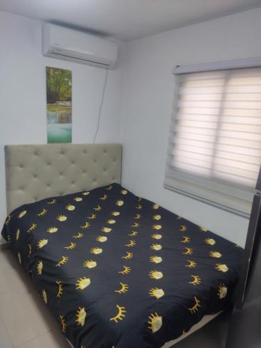 Un dormitorio con una cama con edredón negro y una ventana. en נוף ים אילת, en Eilat