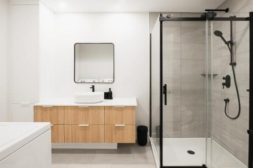 a bathroom with a shower and a sink and a mirror at Villas Perspective-Alphonse-Mont-Ste-Anne in Beaupré