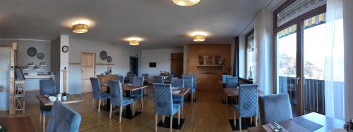 a dining room with blue chairs and tables and windows at Pension Fellis in Vols am Schlern