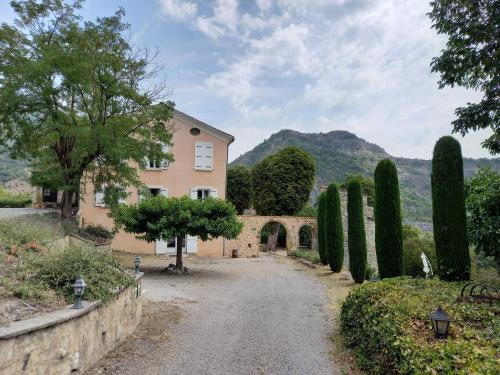 a house with a stone wall and trees and a driveway at Les gîtes du château in La Robine