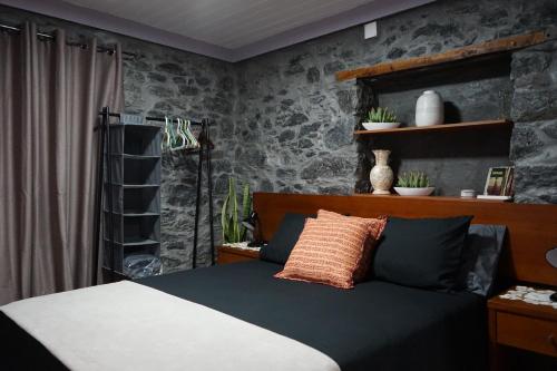 een slaapkamer met een bed en een stenen muur bij Casa do Lombo in Machico