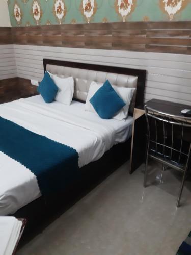 a bed with blue and white pillows and a table at Diamond Imperial in Noida