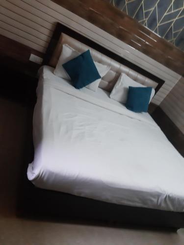 a bedroom with a white bed with blue pillows at Diamond Imperial in Noida