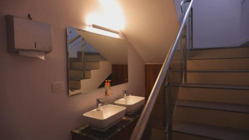a bathroom with two sinks and a staircase with a mirror at Blossom Bed Resort Vagamon by Lexstays in Vagamon