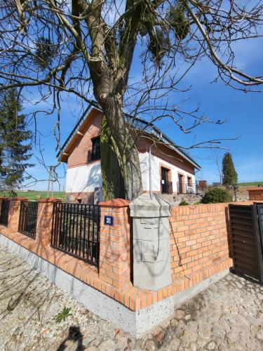 una cerca de ladrillo con un árbol delante de una casa en Stary Dom nad Wrześnicą, 